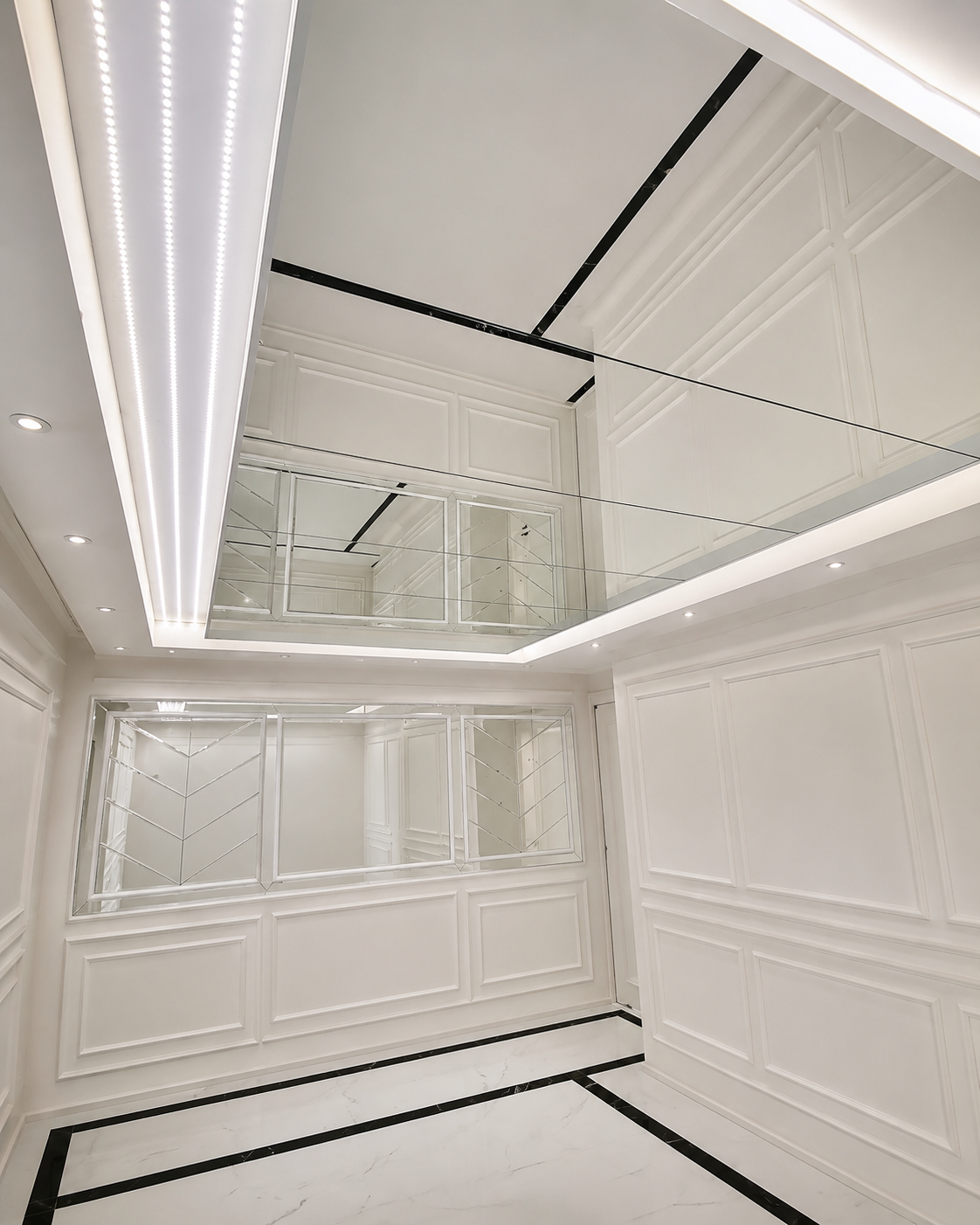 Custom illuminated ceiling mirror and framed geometric wall mirror in a bright luxury interior with white wall moldings.